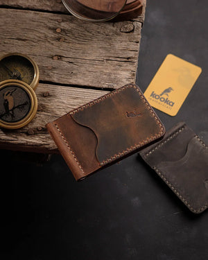 El dikişi deri ikili cüzdan seti, taba ve koyu kahverengi tonlarında Crazy Deri yüzeyiyle öne çıkan Kooka Leathercraft RUN model; Full Grain (Üst Tabaka) derinin doğal renk geçişleri, krem iplik kontrastı ve entegre metal para klipsiyle el işçiliği kalitesini yansıtıyor.