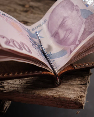 El dikişi deri cüzdan metal para klipsi detayı: taba rengi Crazy Deri yüzeyin doğal dokusu ve dikiş izleriyle birlikte polisaj çelik yay klipsin banknot tutuş açısından yakın çekim görünümü, Full Grain (Üst Tabaka) derinin zengin kahverengi tonu ve işlenmiş kenar kalitesiyle öne çıkan CRAZY model bifold cüzdan.