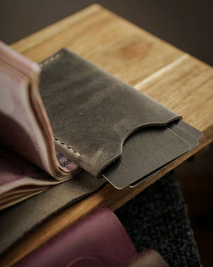 Full Grain (Üst Tabaka) Crazy Deri gri/yeşil tonlu dik cüzdan, angled kart gözü flabından çıkan metal kartlar ve el dikişi işçiliğiyle öne çıkan KOOKA LEATHER STYLE modeli — distressed mat yüzey dokusu ve doğal çizik izleriyle el yapımı kaliteyi yansıtır.