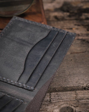 Ahşap tezgahta gri crazy deri kart slotları yakın çekim, Kooka Leather Torn el dikişi ve deri doku detayı görünümü