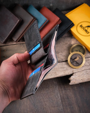 Elde tutulan açık Kooka Leather Azur gri cüzdanın geniş kağıt para cebi, crazy deri patina özelliğiyle sıcak ışıkta dramatik gölgelerle belirginleşiyor.
