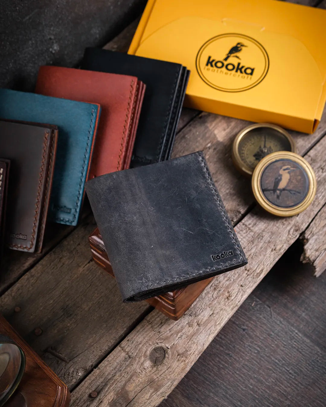 Rustik ahşap üzerinde kapalı duran gri crazy deri Kooka Leather Azur cüzdan, el dikişli detaylarıyla kompakt erkek tasarımı sunuyor.