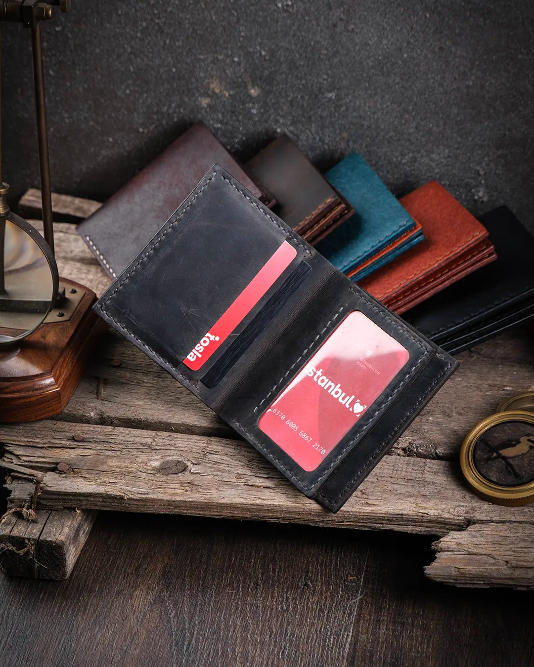Dolu kart slotları ve şeffaf cep içinde net görünen kimlik kartıyla açık Kooka Leather Azur gri crazy deri cüzdan, rustik dokuda sergileniyor.
