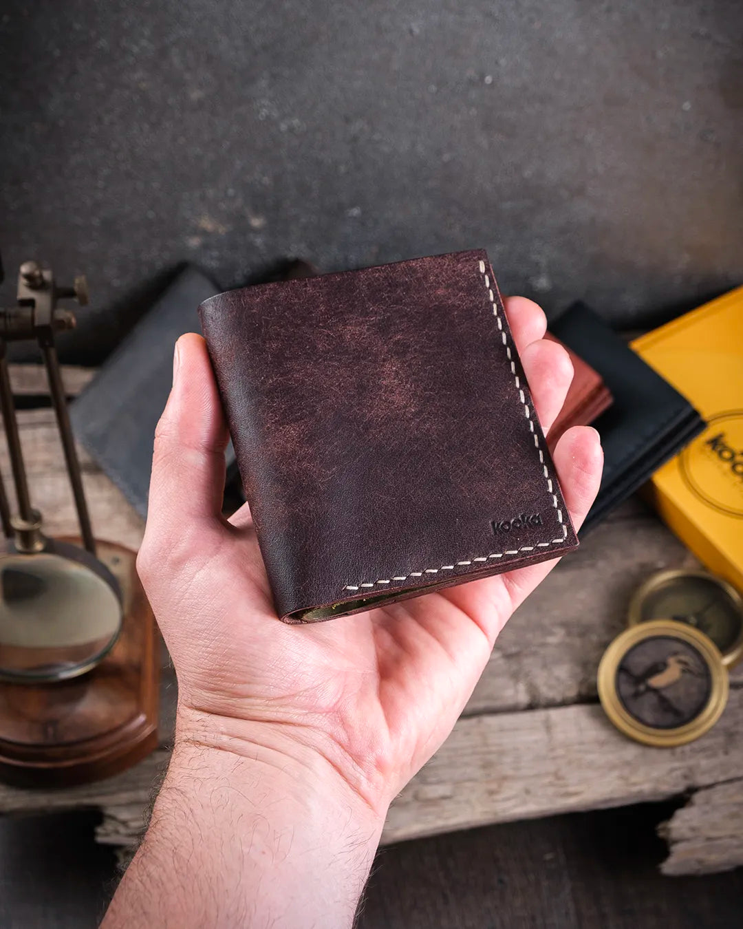 Avuç içine sığan kompakt boyutta kahverengi-olive Azur pueblo deri cüzdan, kapalı halde elde tutuş görünümü, Kooka Leather