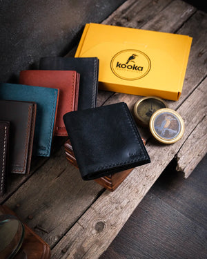 Ahşap yüzeyde el dikişli siyah pueblo deri cüzdan kapalı hali, Kooka Leather Azur kompakt tasarımı ile minimalist erkek tarzı