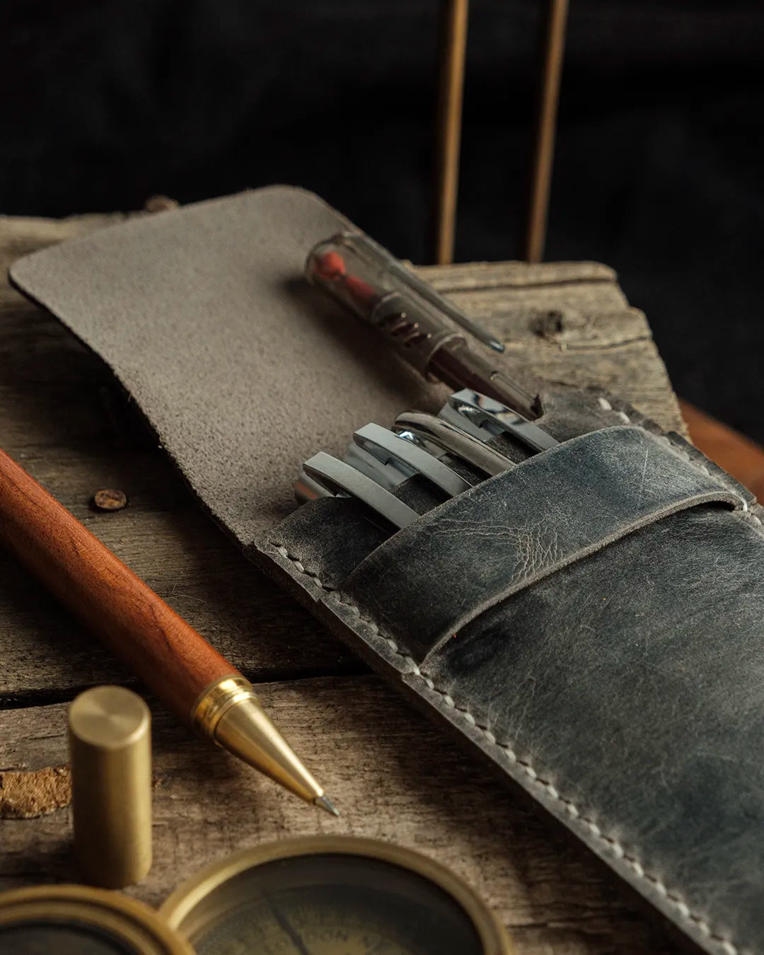 El dikişi gri Crazy Deri dikey kalemlik, kapağı açık konumda içindeki kalemlerle birlikte; distressed dokusu, doğal çizikleri ve pull-up etkisiyle koyu antrasit-gri tonu ön planda. kooka markasına ait Full Grain (Üst Tabaka) Crazy Deri işçiliği, krem renkli el dikişi ve yapılandırılmış kalem yuvalarıyla artisanal kaliteyi yansıtıyor.