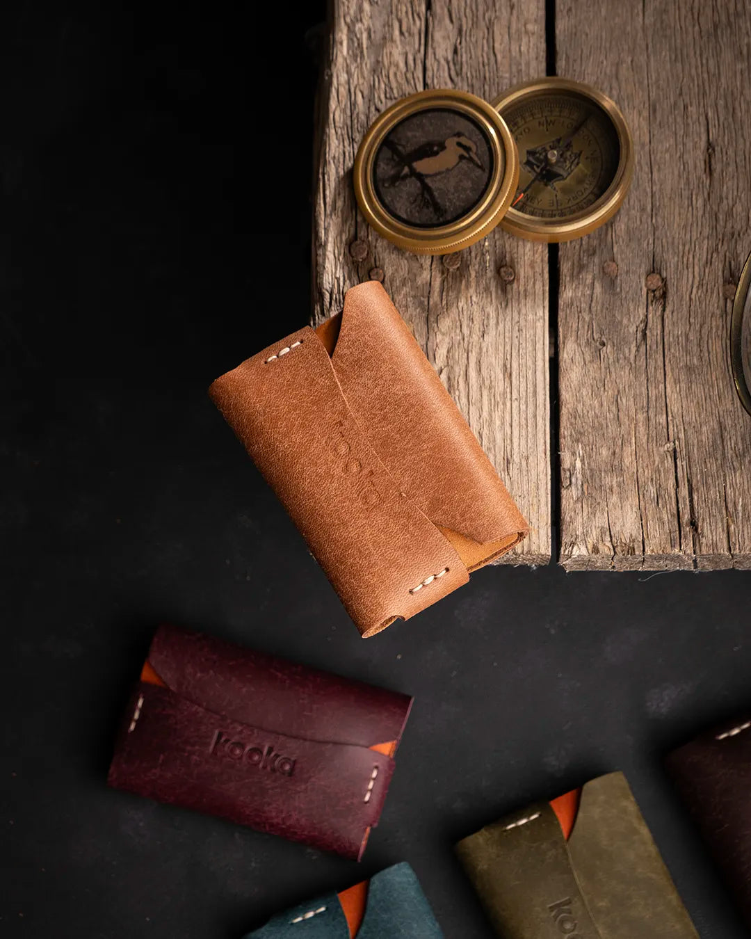 Full Grain (Üst Tabaka) Pueblo deri el dikişi kartlık, karamel kahve tonda zengin dokulu yüzey ve origami katlama tasarımıyla öne çıkan kooka marka minimalist cüzdan — tüm renk serisiyle birlikte kuşbakışı kompozisyon