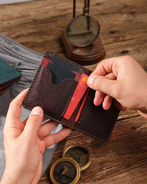 Elde tutulan açık bordo-kahverengi pueblo bifold cüzdan, kart slotundan pratik kart çıkarma hareketi görünümü, Kooka Leather