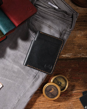 Siyah pueblo deri bifold cüzdan kapalı halde üstten görünüm, kahverengi el dikişi detayı ve dikey form tasarımı, Kooka Leather