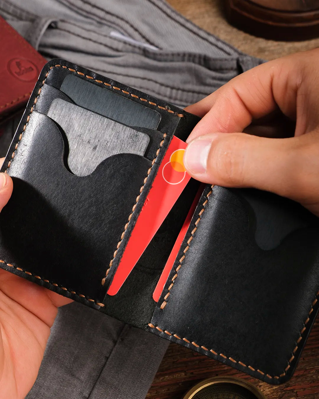Bifold pueblo deri cüzdan açık halde elde, iç kart slotundan kart çıkarılıyor, el dikişi detaylı tasarım, Kooka Leather