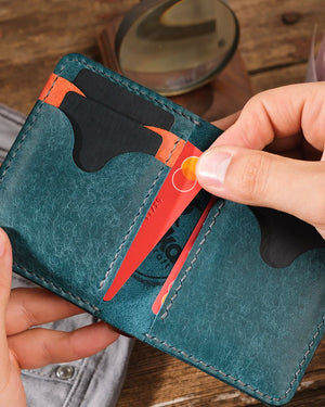 Çok kartlı pueblo deri cüzdan açık halde elde, kart slotundan bir kartın çıkarıldığı an yakın plan çekim, Kooka Leather OZN