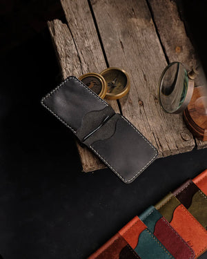 El dikişi deri para klipsli cüzdan, siyah Pueblo derisiyle üretilmiş; açık konumda iç yapısı ve entegre metal para klipsi görünür halde, dalgalı kart gözü kesimi ve çift taraflı el dikişiyle titiz işçilik sergileniyor. RUN marka bu slim bifold modeli koyu siyah deri yüzeyiyle mat bir görünüm sunarken, sağ alt köşede ürünün farklı renk seçenekleri (turuncu, yeşil, kiremit, bordo) sıralanmış şekilde yer alıyor.