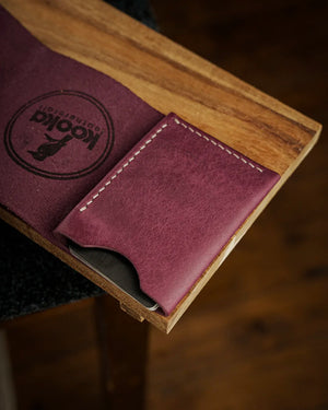 El dikişi krem kontrast dikiş detayıyla mor PUEBLO deriden kooka Style bifold cüzdan, açık kart gözü ve tam tahıl deri dokusunun belirgin yüzeyiyle sergileniyor