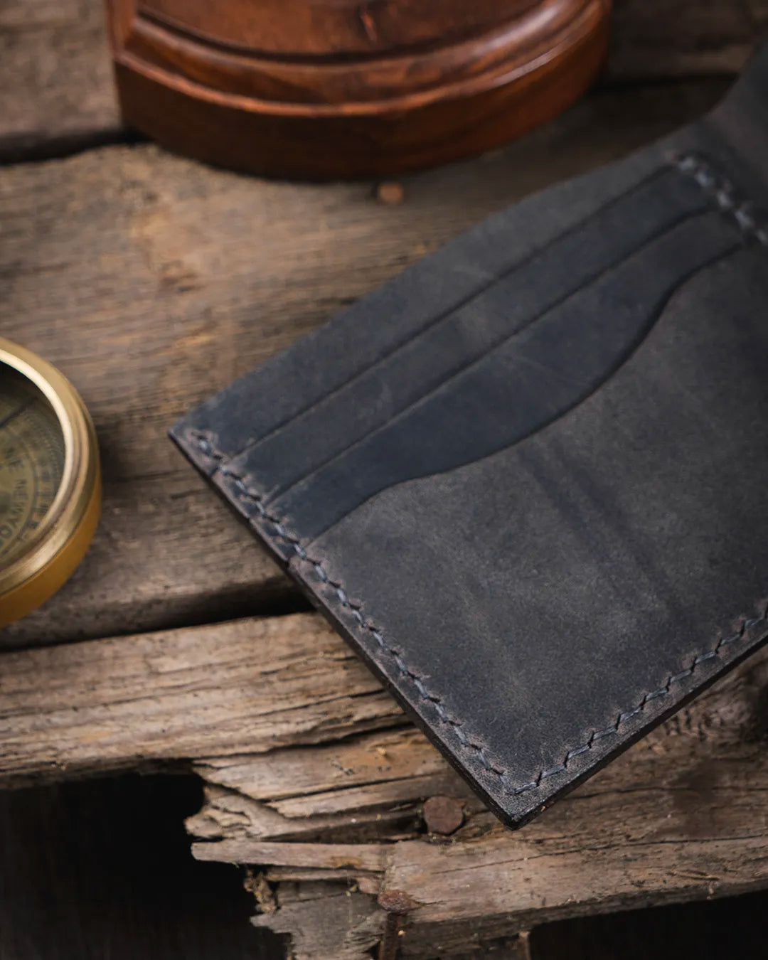 Rustik ahşap zemin üzerinde gri crazy deri doku detayı yakın çekim, Kooka Leather Torn cüzdan patina yüzey görünümü