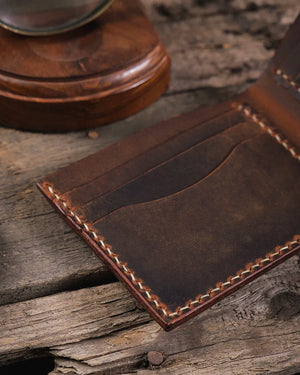 Rustik zemin üzerinde taba hakiki deri Kooka Leather Torn bifold cüzdan açık halde kart slotları yakın detay