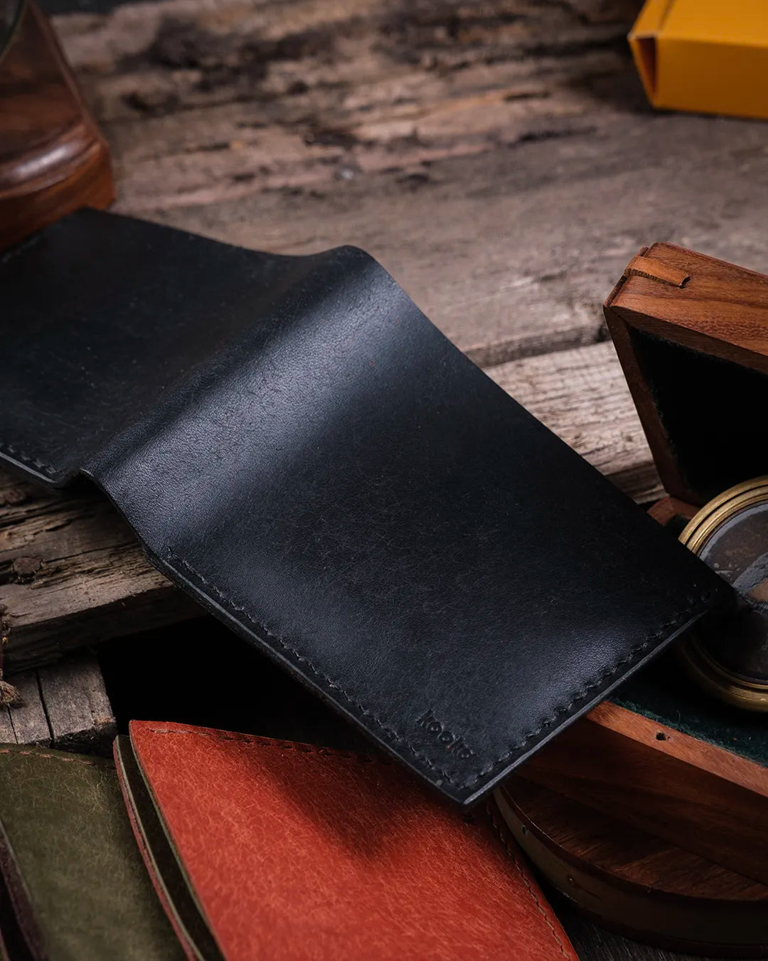 Sıcak ışık yansımasıyla ahşap yüzeyde açık durumda siyah hakiki deri cüzdan dış yüzey dokusu, Kooka Leather klasik tasarım