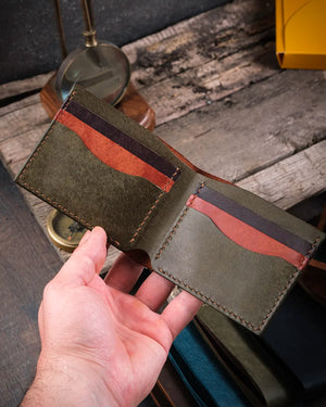 El yapımı pueblo deri bifold cüzdan elde açık tutuş, iç tasarım ve kart bölmeleri sıcak ışıkta görünüm, Kooka Leather