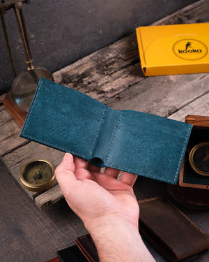 El yapımı mavi pueblo deri cüzdan elde tutuluyor, açık konumda kartlık bölümleri ve para haznesi görünüyor, Kooka Leather