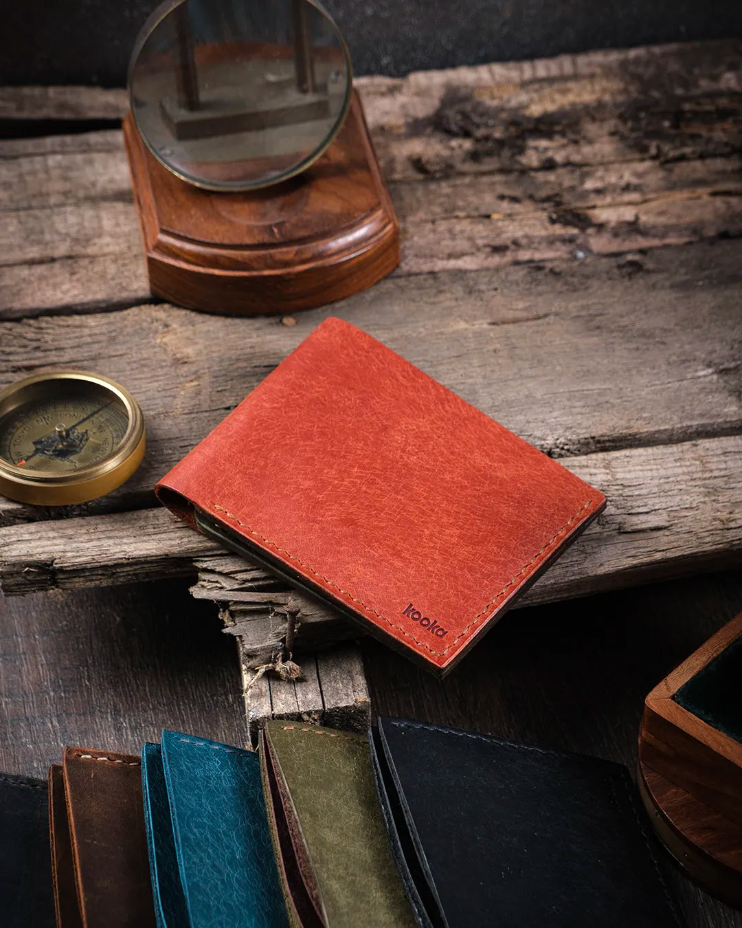 Ahşap yüzeyde kapalı halde taba pueblo deri Kooka Leather Torn kompakt cüzdan, dış yüzey doku ve el dikişi detayı
