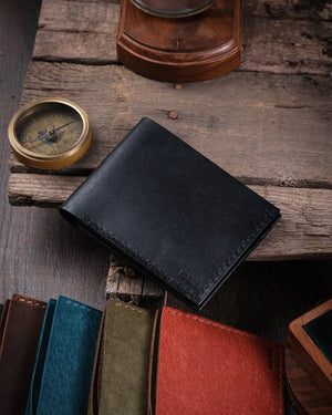 Sıcak ışıkta ahşap yüzeyde dikdörtgen formlu kapalı siyah pueblo deri kompakt cüzdan, Kooka Leather tasarımı