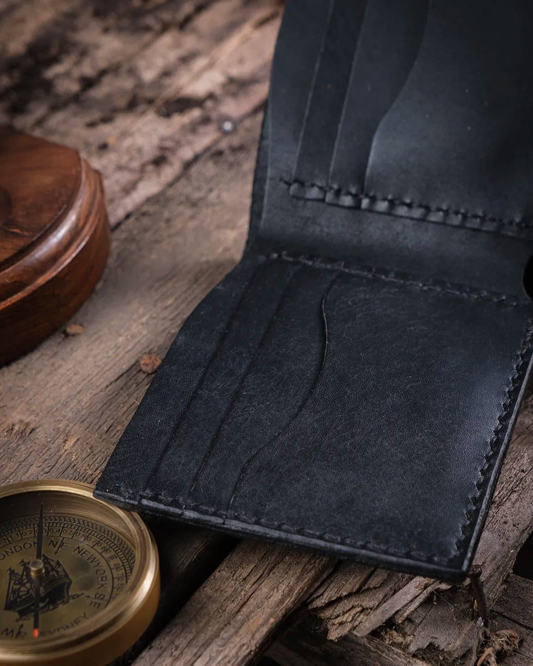 Rustik ahşapta el dikişi detaylı siyah hakiki deri erkek cüzdan, Kooka Leather pueblo deri işçiliği yakın plan