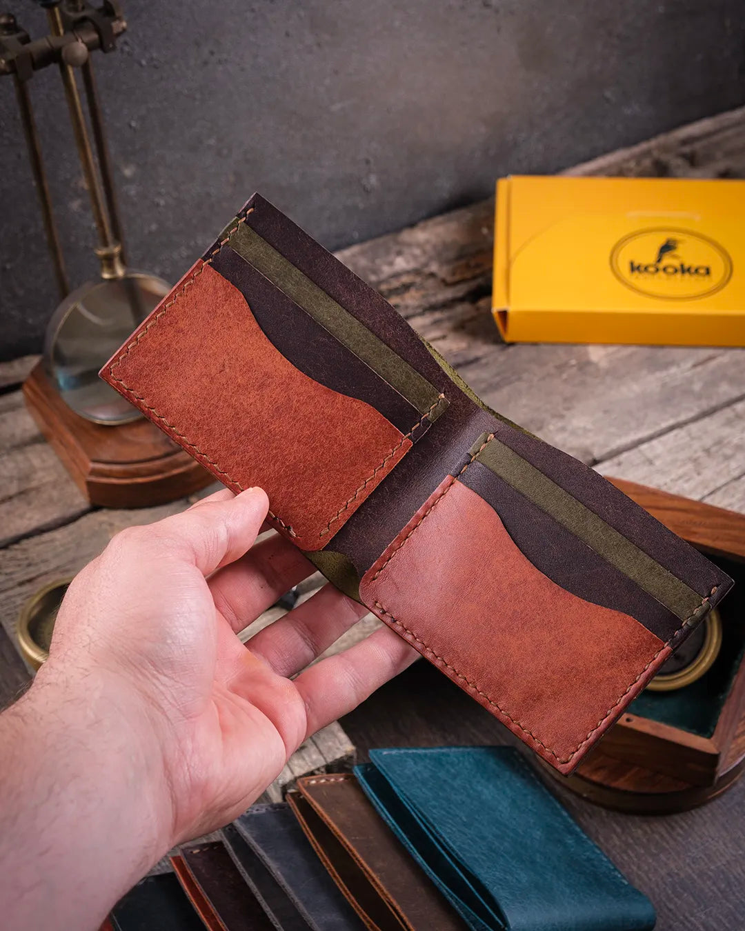 Sıcak ışıkta elde tutulan açık haldeki pueblo deri erkek cüzdanın iç yapısı ve el dikişi detayları, Kooka Leather