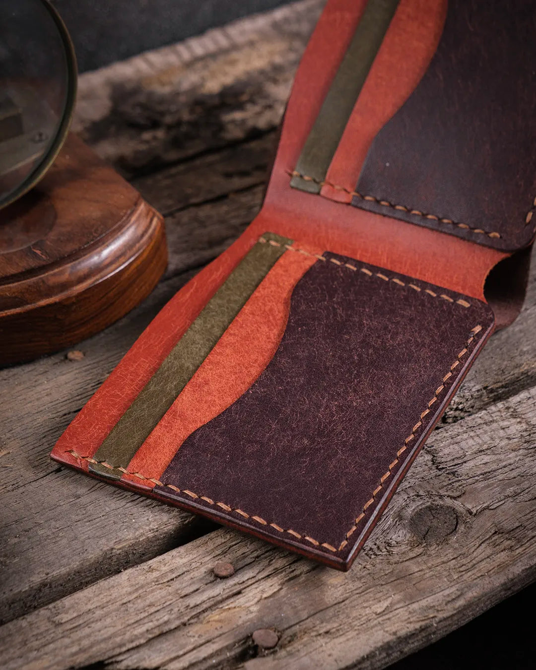 Rustik ahşap yüzeyde Kooka Leather Torn hakiki pueblo deri bifold cüzdan, 6 kartlık bölmelerin yakın çekim detayı